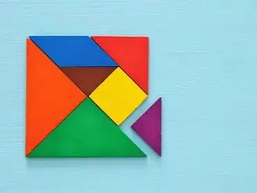 A colorful tangram puzzle on a light blue background, missing one piece. The puzzle comprises triangles, a square, and a parallelogram in vibrant colors such as red, green, yellow, blue, orange, and purple. The purple triangle piece is positioned outside the main shape.